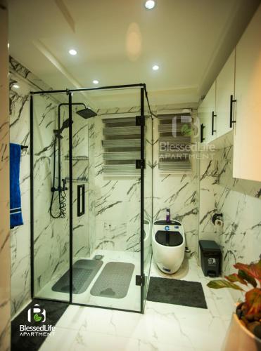 a bathroom with a glass shower with a toilet at Blessedlife Apartment in Kumasi