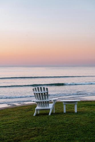 a white chair sitting on the grass next to the ocean at Cutty Sark Motel in York Beach