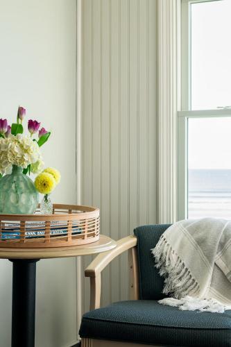 a table with a vase of flowers and a chair at Cutty Sark Motel in York Beach