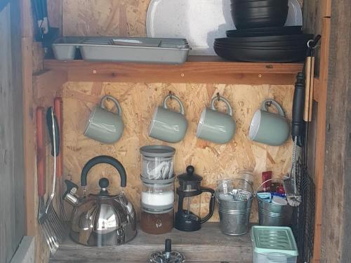una mensola con pentole, padelle e altri utensili da cucina di Fairy Hill at Rosemount Glamping a Carlingford