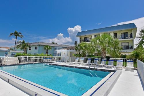 a swimming pool with chairs and a building at Anna Maria Island Beach Sands in Bradenton Beach