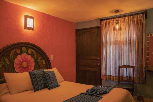 a bedroom with a bed with a flower painted on the wall at Hotel Tepeyac in San Cristóbal de Las Casas