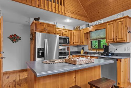 a kitchen with wooden cabinets and a stainless steel refrigerator at The Cabin Kingdom Hot tub Fire Pit in Blairsville