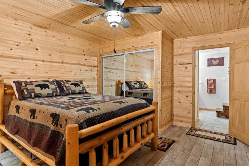 a log cabin bedroom with a bed and a ceiling fan at The Cabin Kingdom Hot tub Fire Pit in Blairsville