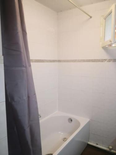 La salle de bains blanche est pourvue d'une baignoire et d'un rideau de douche. dans l'établissement Hébergement 4 pièces à Marseille près du Vélodrome, à Marseille