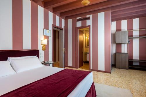 a bedroom with a bed and a striped wall at Hotel Tiziano in Venice