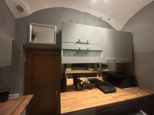 a kitchen with white cabinets and a wooden floor at Studio Old Town in Maribor