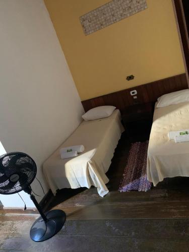 a room with two beds and a chair in it at Solar Colonial Pousada in Iguape