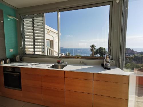 une cuisine avec un évier et une grande fenêtre dans l'établissement VILLA HELIOS - vue mer, terrasse, jardin, piscine, parking, à Marseille