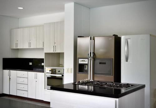 a kitchen with white cabinets and a stainless steel refrigerator at Magnifica finca santa fe de Antioquia in Santa Fe de Antioquia