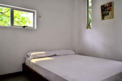 a white bedroom with two beds and a window at Magnifica finca santa fe de Antioquia in Santa Fe de Antioquia