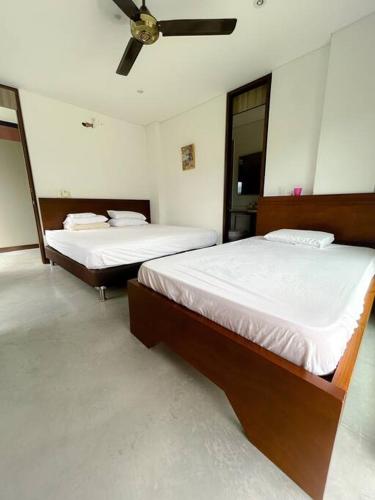 two beds in a room with a ceiling fan at Magnifica finca santa fe de Antioquia in Santa Fe de Antioquia