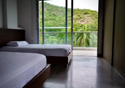 two beds in a room with a large window at Magnifica finca santa fe de Antioquia in Santa Fe de Antioquia