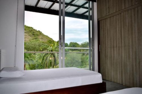 a bedroom with a large window and a white bed at Magnifica finca santa fe de Antioquia in Santa Fe de Antioquia