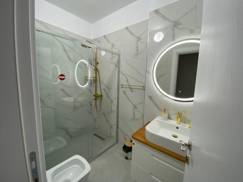a bathroom with a shower and a sink and a mirror at VloraGB Apartment in Vlorë