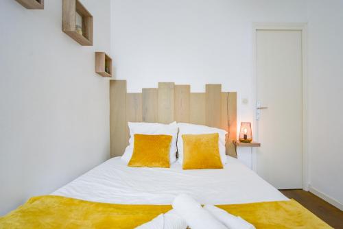 une chambre avec un lit avec des draps blancs et des oreillers orange dans l'établissement Le Cocon Des Prébendes - Hypercentre - Netflix, à Tours