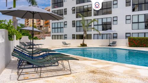 a pool with lounge chairs and an umbrella and a building at Acapulco Retreat with Bay Views & Amenities in Acapulco