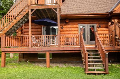 a wooden cabin with a staircase and an umbrella at Auberge Couleurs de France in Lac-Simon