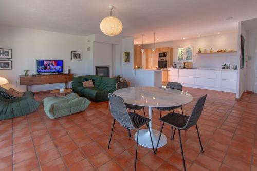 un salon avec une table et des chaises et une cuisine dans l'établissement Villa Le Soleil Bleu - Piscine - Jardin, à Le Tignet