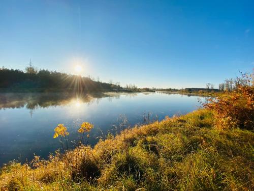 a view of a river with the sun in the background at Dom w krainie Bugu in Korczew