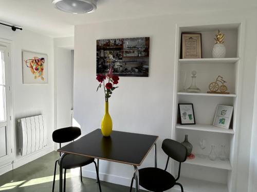 une salle à manger avec un vase et des fleurs sur une table dans l'établissement Unit 018 Saint Germain des Près - one bedroom apartment 4 pax, à Paris