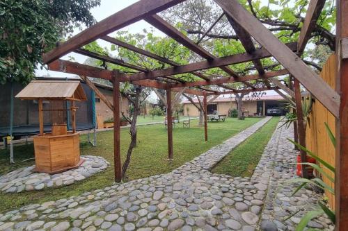 a garden with a wooden pergola and a stone path at Casa de Campo para desconectarse de la ciudad in Rancagua