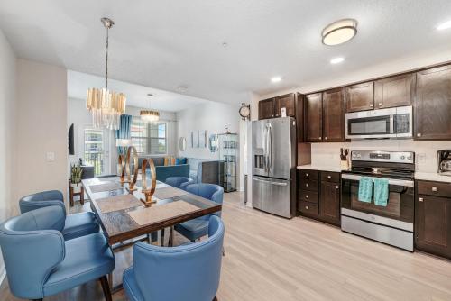 a kitchen with a wooden table and blue chairs at Luxury 3BR resort Condo walking distance to Epic Universe, Convention center and Icon Park in Orlando