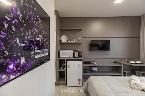 a hotel room with a refrigerator and a tv at MHFA - Studios em Prédio Luxuoso com Vista Mar in Itapema