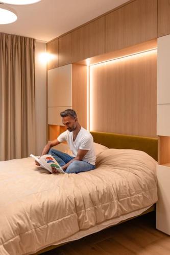 a man sitting on a bed reading a book at Henry's Appt with a private Suite 414 - Shared kitchen in Luxembourg