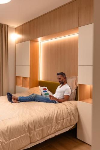 a man sitting on a bed reading a book at Henry's Appt with a private Suite 414 - Shared kitchen in Luxembourg