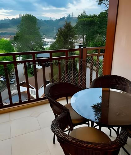 a table and chairs on a balcony with a view at Apartamentos Centrinho Capivari - Recanto Boticário in Campos do Jordão