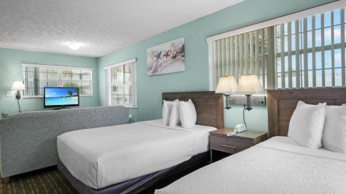 デイトナビーチにあるOcean Court Beachfront Hotelのベッド2台と薄型テレビ付きのホテルの部屋