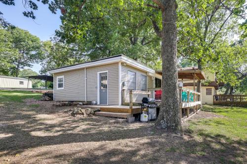 a tiny house with a porch and a tree at Deck and Dock Access Lakefront Grove Cabin! in Grove