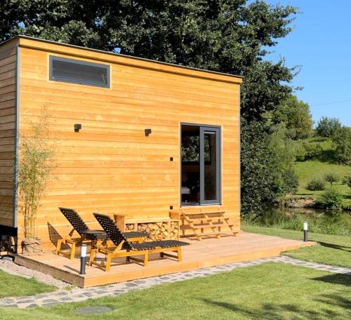 ein winziges Haus mit einer Terrasse und Stühlen in der Unterkunft Tiny U Labe in Pardubice