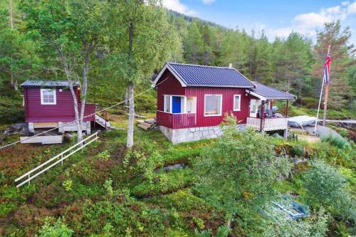 a red cabin in the middle of a forest at Cozy cabin with a great view in Skamdal