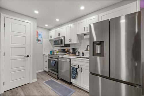a kitchen with white cabinets and a stainless steel refrigerator at Meriweather - Calgary Breathtaking 1-bedroom apartment in Calgary