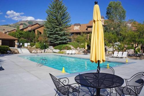ein gelber Regenschirm auf einem Tisch neben einem Pool in der Unterkunft Siggi's Longhorn Lodge in Eden