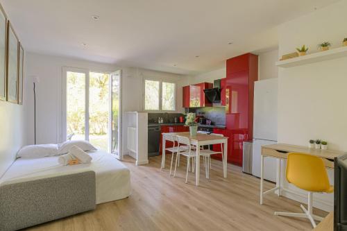 Cet appartement comprend une chambre avec un lit et une cuisine avec des placards rouges. dans l'établissement Joli appartement à Caluire avec parking et jardin, à Caluire-et-Cuire