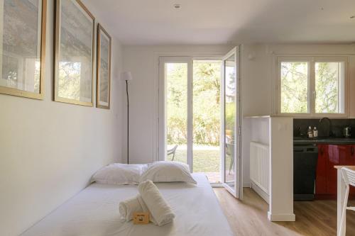 a white bedroom with a bed and a kitchen at Joli appartement à Caluire avec parking et jardin in Caluire-et-Cuire