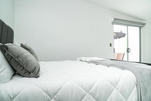 a white bed with pillows in a white bedroom at Home 333 habitacion 336 in Escazu