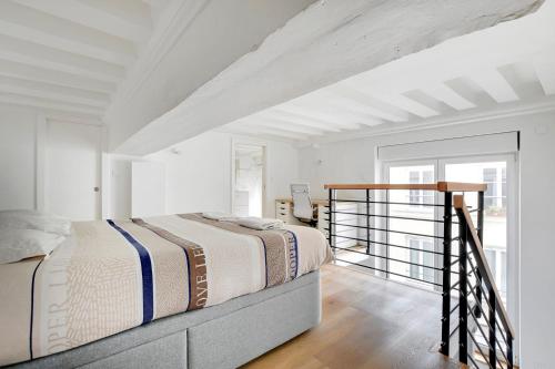 une chambre blanche avec un lit et un balcon dans l'établissement Duplex Notre-Dame de Paris, à Paris