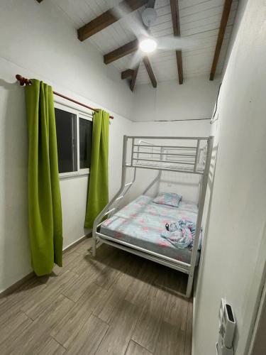 a small bedroom with a bunk bed with green curtains at Bethanie in Le Gosier