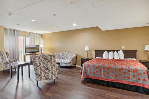 a hotel room with a bed and chairs and a television at Miami Suites in Toledo