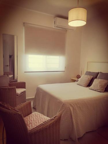 a bedroom with a bed with two chairs and a window at Ela in Playa del Carmen