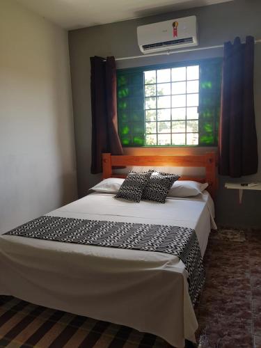 a bedroom with a large bed with a window at Pouso Tião da Morena Suítes Êconomicas in Pirenópolis
