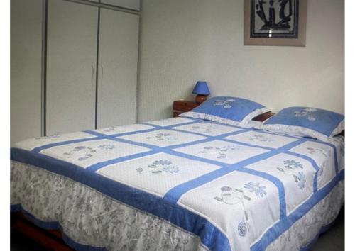 a bed with a blue and white quilt on it at LE LAGON BLEU, BUNGALOWS Vue sur MER , 350 m de la plage in Sainte-Anne