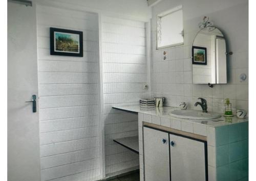 a white bathroom with a sink and a mirror at LE LAGON BLEU, BUNGALOWS Vue sur MER , 350 m de la plage in Sainte-Anne
