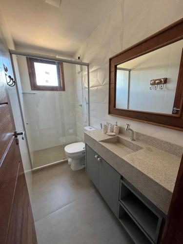 a bathroom with a sink and a toilet and a mirror at Apartamento Barra VIP in Marau