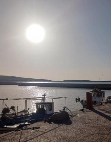 two boats are docked at a dock in the water at Seafront & Sunsets Sigri House in Sígrion
