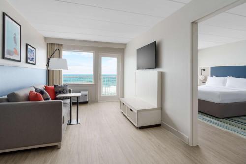 a large hotel room with a bed and a couch at Hilton Garden Inn Ocean City Oceanfront in Ocean City